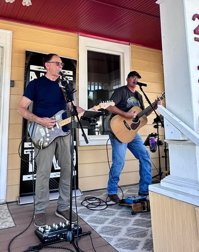 Two guitarists playing live on a porch at BruBash