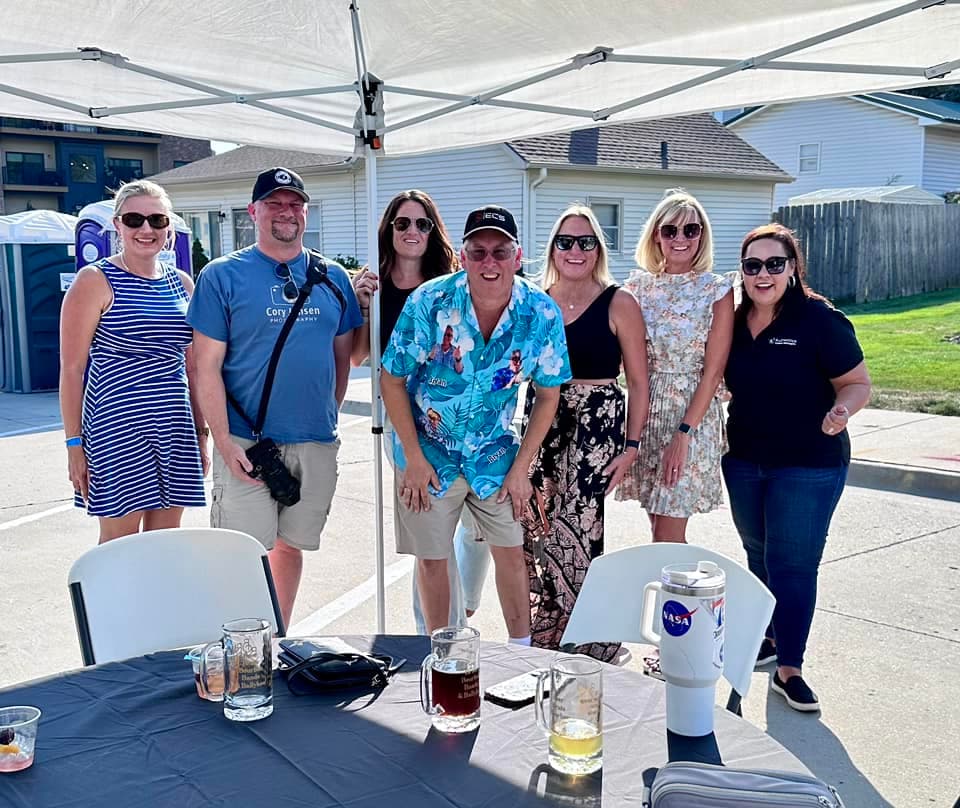A group of guests gathered under the tent with BruBash steins on the table